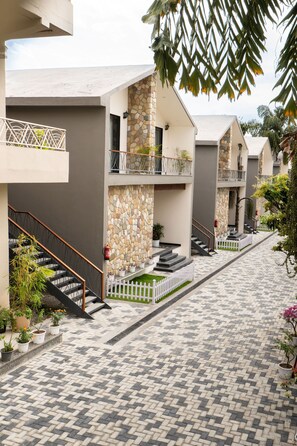 A hotel corridor with multiple balconies, stone walls, and a tiled walkway. - juSTa Nature's Nest Resort (Rishikesh)