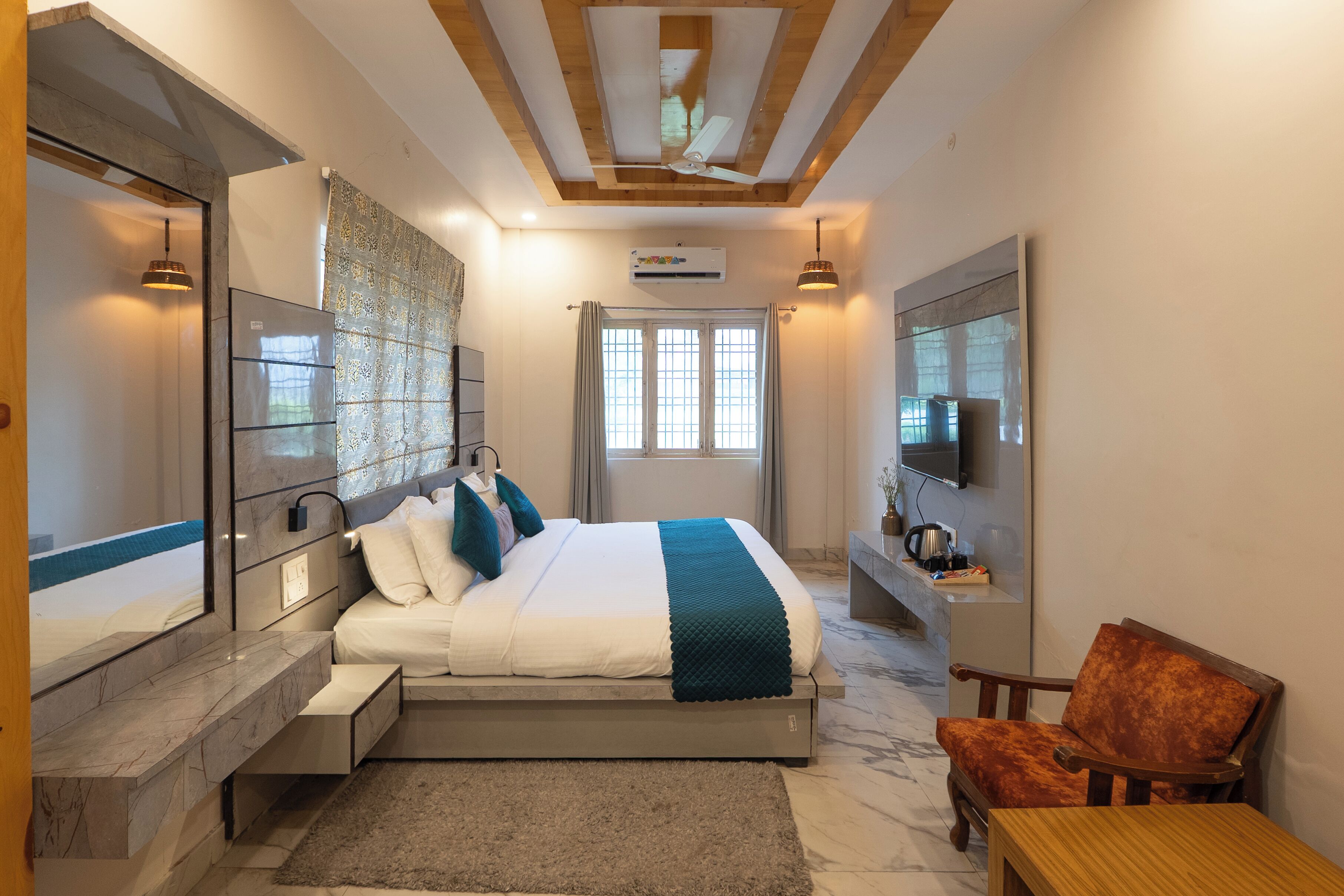 A modern bedroom with a large bed, a flat-screen TV, a wooden ceiling, and a marble floor.
