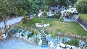 A residential property with a stone pathway, a fenced yard, and a house with a covered outdoor area.