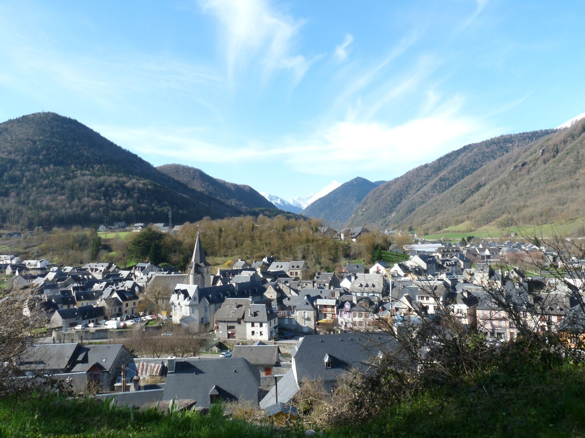 A town with a prominent church, surrounded by mountains and residential buildings.