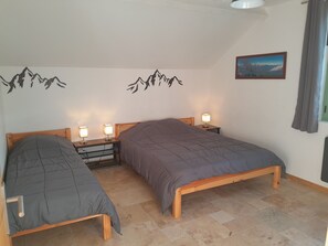 Ein Schlafzimmer mit zwei Betten, Nachttischen mit Lampen, einem Bild an der Wand und einem Fenster mit Vorhängen.