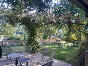 An outdoor patio with a pergola covered in flowers, a wooden fence, and outdoor furniture.
