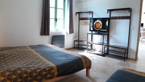 Une chambre à coucher avec un lit, une petite table, un téléviseur et un portant à vêtements.