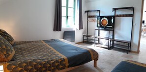 Ein Schlafzimmer mit Bett, einem kleinen Tisch, einem Fernseher und einem Kleiderständer.