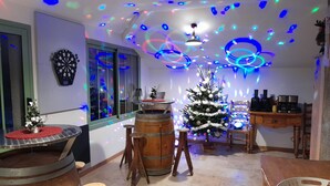 Une pièce décorée d’un sapin de Noël, dotée d’un jeu de fléchettes et d’un coin bar avec des tabourets.