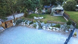 Il s’agit d’une propriété résidentielle dotée d’une allée gravillonnée, d’un abri de jardin en bois, d’un chemin en pierre et d’un jardin clos, agrémenté de diverses plantes.