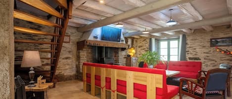 Een rustiek interieur met een houten bank, stenen muren en een open haard.