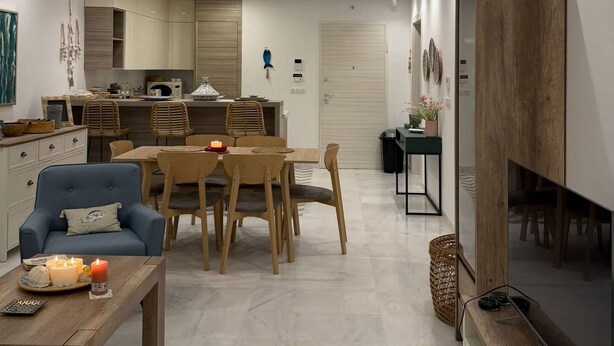Ein modernes Wohnzimmer mit Essbereich, einem Fernseher und einer Küche im Hintergrund.