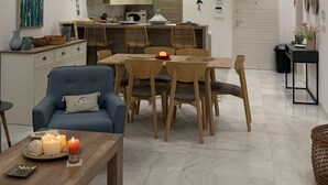 Ein modernes Wohnzimmer mit Essbereich, einer dahinterliegenden Küche und einer Deckenleuchte.