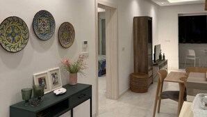 Ein modernes Wohnzimmer mit einer Konsole, dekorativen Tellern, einem Holzschrank und einem Essbereich mit Stühlen und Tisch.