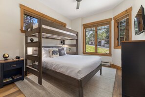 A bunk bed with a desk and globe, a TV, and large windows with a view of greenery. - Steps from Slopes | Winter Shuttle | Pool & Hot Tub (Steamboat Springs)