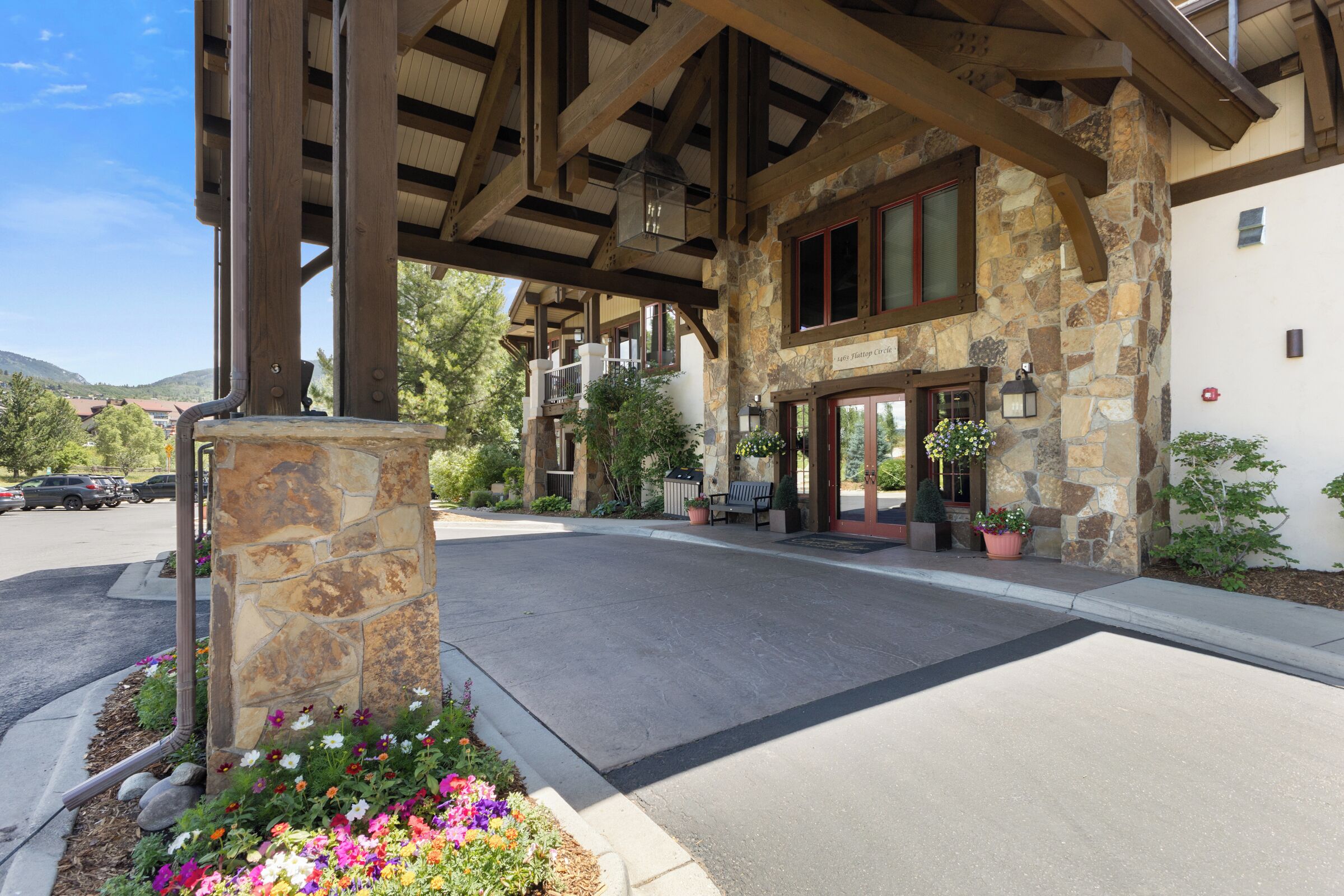 A stone building with a covered entrance, outdoor seating, and a flower bed.