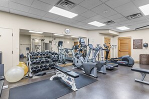 A gym with exercise equipment, a mirror, and a clock on the wall. - Steps from Slopes | Winter Shuttle | Pool & Hot Tub (Steamboat Springs)