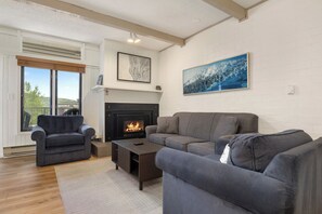 Ein Wohnzimmer mit Kamin, einer Couch, einem Couchtisch und einem Gemälde an der Wand.