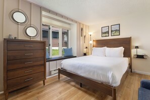 A bedroom with a wooden bed, a dresser, a window with a view, and two wall-mounted lamps. - Slopeside | Hot Tub | Bonus Den with Video Games (Steamboat Springs)