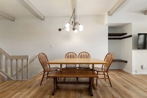 A dining area with a wooden table and chairs, a chandelier, and a staircase. - Slopeside | Hot Tub | Bonus Den with Video Games (Steamboat Springs)
