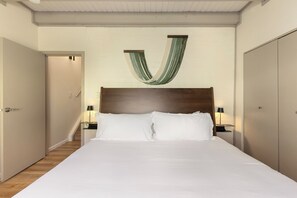 Ein Hotelzimmer mit einem großen Bett, zwei Nachttischen mit Lampen, einem hölzernen Kopfteil und einer grünen und weißen Stoffdekoration.