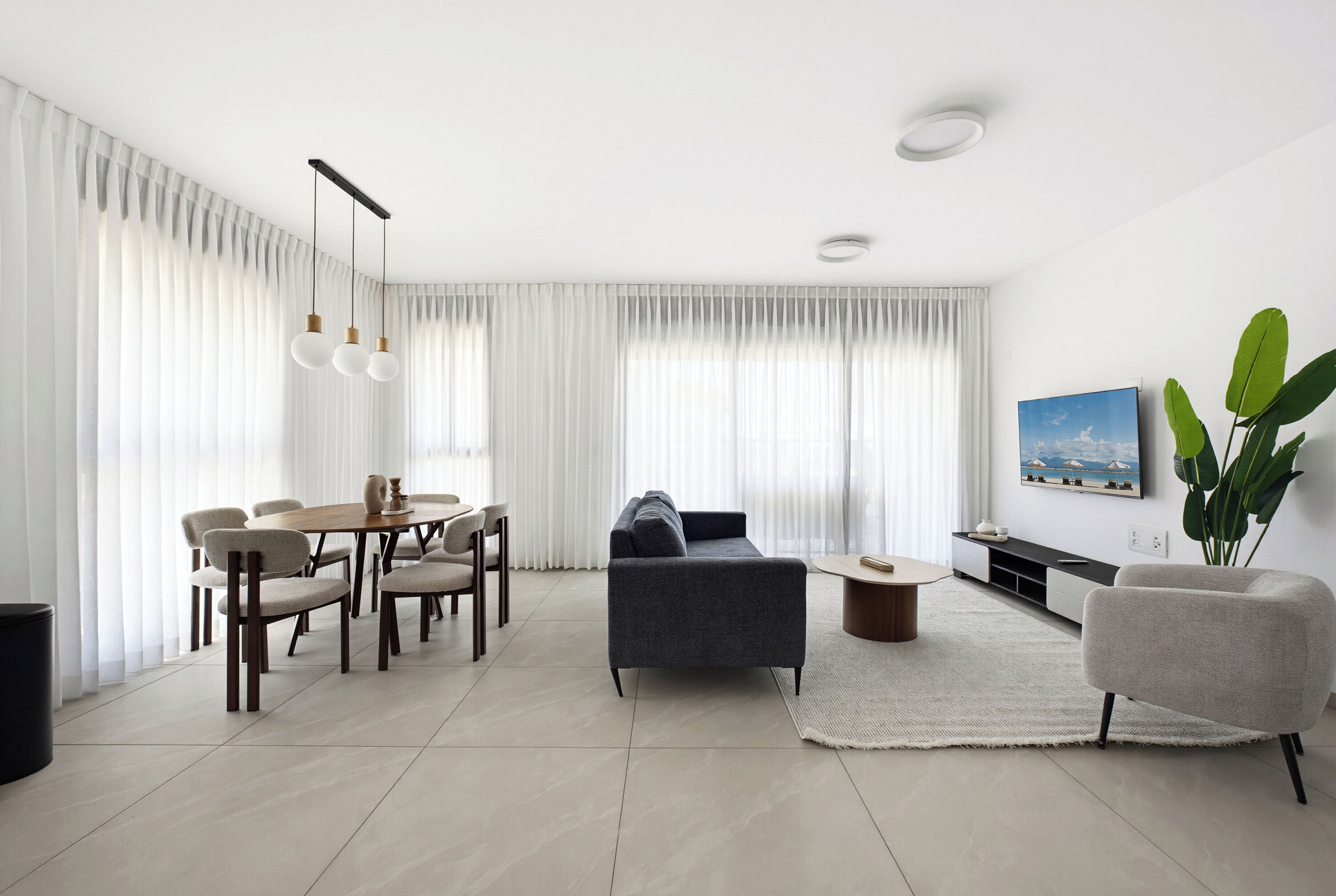 Una sala moderna con sofá, mesa de comedor, sillas y televisor.