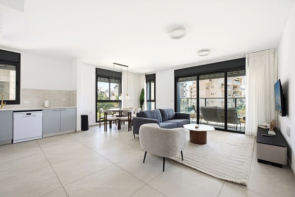 A modern apartment with a kitchen, dining area, living room, and large windows. - Spacious 4BR Apt l Sunny Balcony & Mamad (Rishon LeTsiyon)