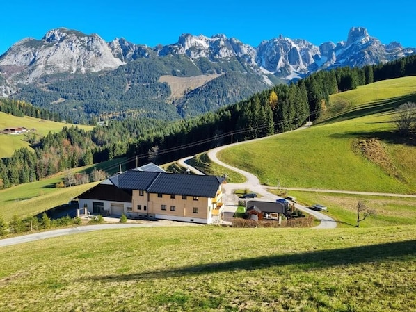 A house with a curved driveway, surrounded by green fields and mountains. - Ferienwohnungen Unterdürmoos Apartments mit Chalet-Charme auf 1050 m, Alleinlage (Promberg)