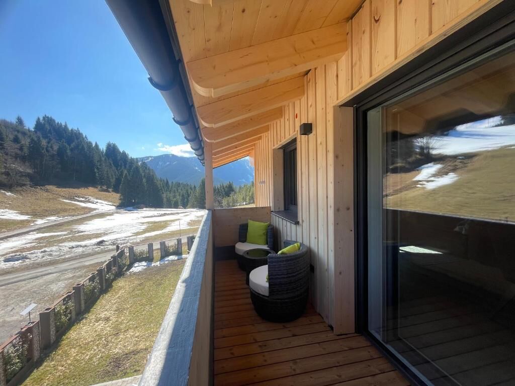 A wooden balcony with a view of a snowy landscape and mountains.