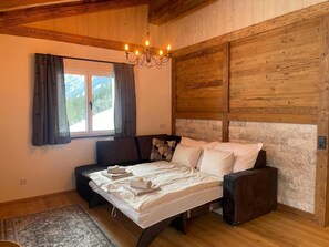 Een kamer met een bed, een bank, een kroonluchter en een raam met gordijnen.