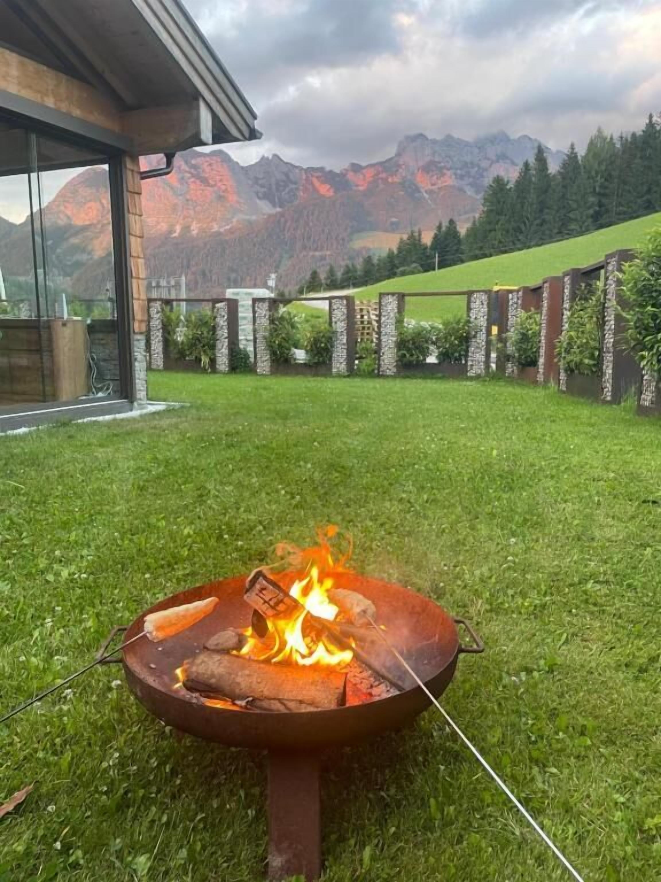 Un patio trasero con una chimenea, césped y vistas a la montaña.