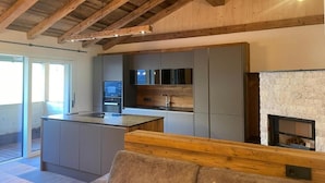 Una cocina moderna con una isla central, electrodomésticos integrados y una chimenea de piedra.