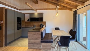 Una cocina moderna con vigas de madera, un comedor con banco y un ventanal grande.