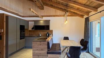 A modern kitchen with wooden beams, a dining area with a bench, and a large window.