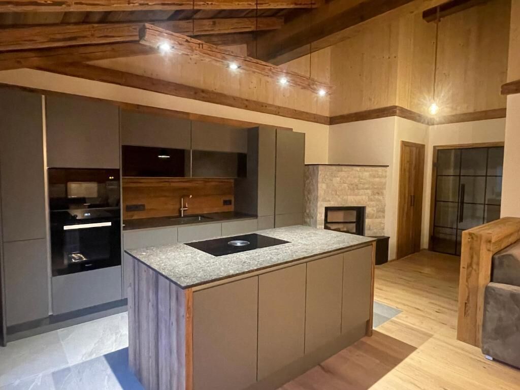 Una cocina moderna con una isla central, electrodomésticos integrados y una pared decorativa de piedra.
