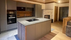 Una cocina moderna con una isla central, electrodomésticos integrados y una pared decorativa de piedra.