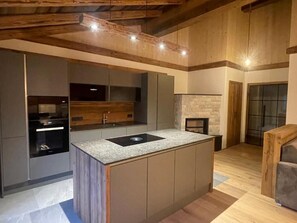 Eine moderne Küche mit Kochinsel, integrierten Geräten und einer Wand mit Steinverkleidung.