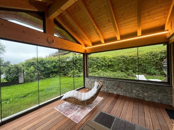 A modern room with a large glass window, wooden flooring, and a stone wall. - Ferienwohnungen Unterdürmoos Apartments mit Chalet-Charme auf 1050 m, Alleinlage (Promberg)