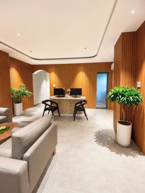 A modern reception area with a reception desk, two chairs, a sofa, and potted plants. - Corner Inn Ben Thanh Hotel (Ho Chi Minh City)