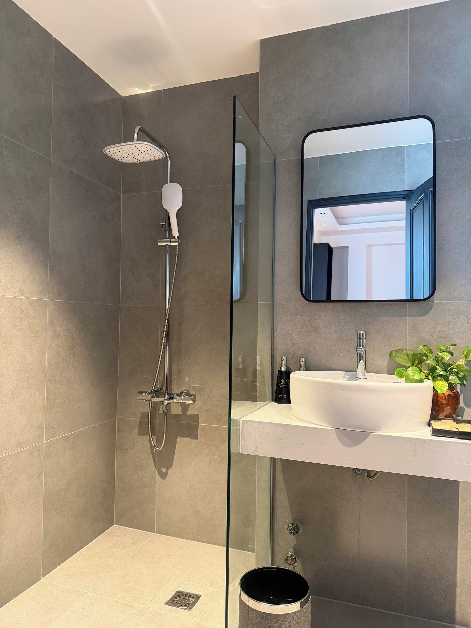 A modern bathroom with a glass shower enclosure, a white sink, and a mirror.