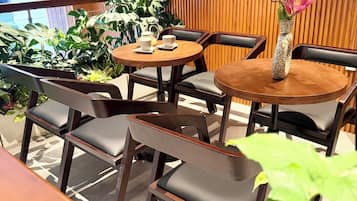 Un espace extérieur aménagé avec des tables et des chaises en bois, entouré d’une végétation luxuriante.