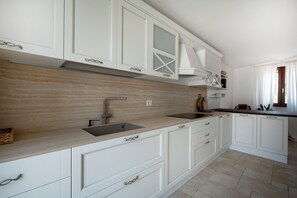 A modern kitchen with white cabinetry, a wooden countertop, and a built-in stove. - Beyond the Coni – An Oasis of Relaxation (MONOPOLI)