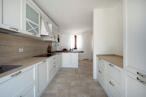 A modern kitchen with white cabinetry, a wooden countertop, and a built-in oven. - Beyond the Coni – An Oasis of Relaxation (MONOPOLI)