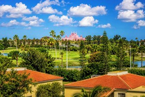 Ein rosafarbenes Resort mit Golfplatz, Palmen und einem See.