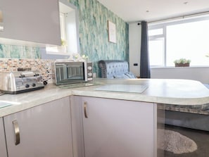Eine moderne Küche mit einem Toaster, einer Mikrowelle und einem Stuhl in der Nähe eines Fensters.