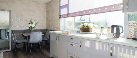 Une cuisine moderne avec un coin repas, comprenant une fenêtre avec vue, un évier et une machine à café.