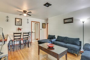 Ein Wohnzimmer mit Holzboden, einem dunkelblauen Sofa, einem Couchtisch und einem Deckenventilator.