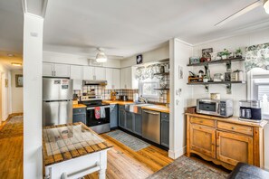 A kitchen with a wooden table, stainless steel appliances, and a coffee maker on a shelf. - Block and Half to Beach! Minutes From AC, Casinos (Brigantine)