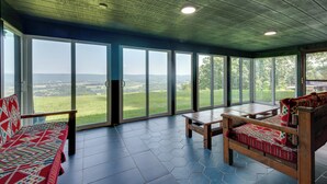 A room with a large sliding glass door, a wooden bench, and a wooden table. - Luxury Tudor Estate | Pool, Spa and Valley Views (Hazleton)