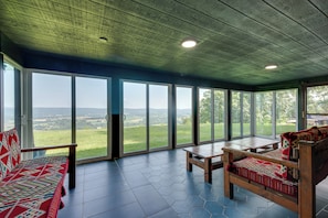 A room with a large sliding glass door, a wooden bench, and a wooden table. - Luxury Tudor Estate | Pool, Spa and Valley Views (Hazleton)
