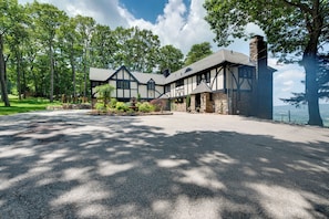 A large, two-story house with a stone chimney, surrounded by a well-maintained lawn and trees. - Luxury Tudor Estate | Pool, Spa and Valley Views (Hazleton)