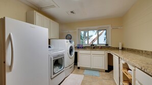 A kitchen with a refrigerator, washing machine, oven, and a window with a view. - Luxury Tudor Estate | Pool, Spa and Valley Views (Hazleton)