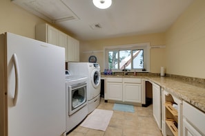 A kitchen with a refrigerator, washing machine, oven, and a window with a view. - Luxury Tudor Estate | Pool, Spa and Valley Views (Hazleton)