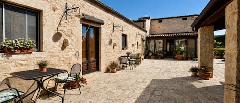A courtyard with stone walls, outdoor seating, and potted plants.